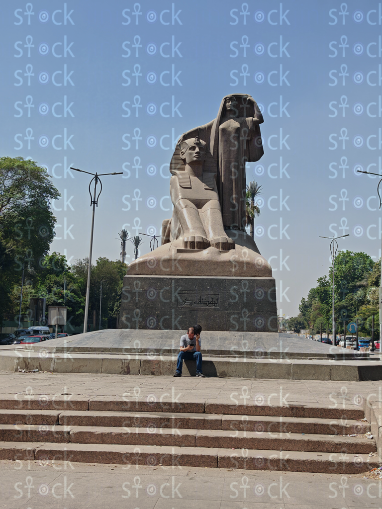 A person resting on the stairs in front of the statue