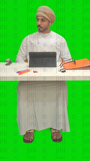 An Omani man from the Gulf working on a tablet computer in his office and thinking about a vacation or the weekend