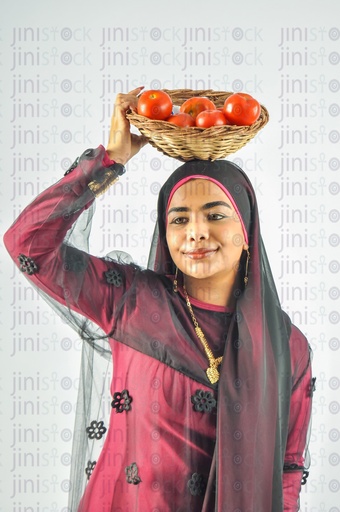 A Nubian woman from Egypt wearing Nubian clothes and putting a plate of tomatoes on her head.