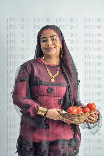 A Nubian woman from Egypt wearing Nubian clothes and holding a plate of tomatoes in her hands