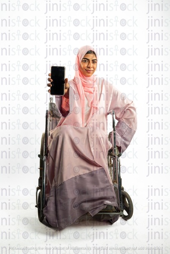 saudi khaliji woman from the gulf on a wheel chair disabled and  holding a mobile and poiniting it to the camera