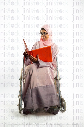 امرأة خليجية سعودية من الخليج على كرسي متحرك تنظر إلى ملف أو مجلد عمل