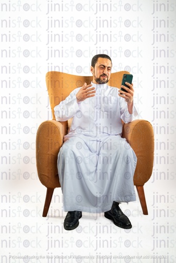 saudi khaliji man sitting on the chair happy looking at his mobile phone