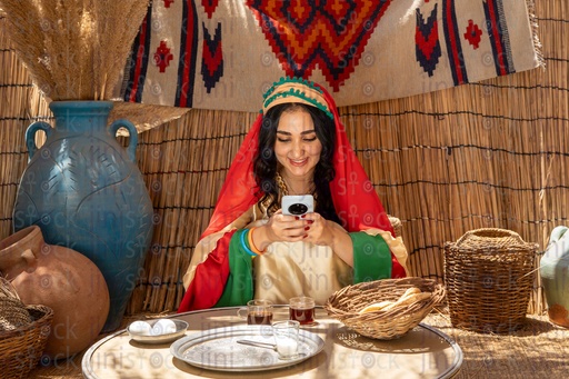 فلاحة مصرية تجلس في الكوخ تنظر لهاتفها مبتسمه